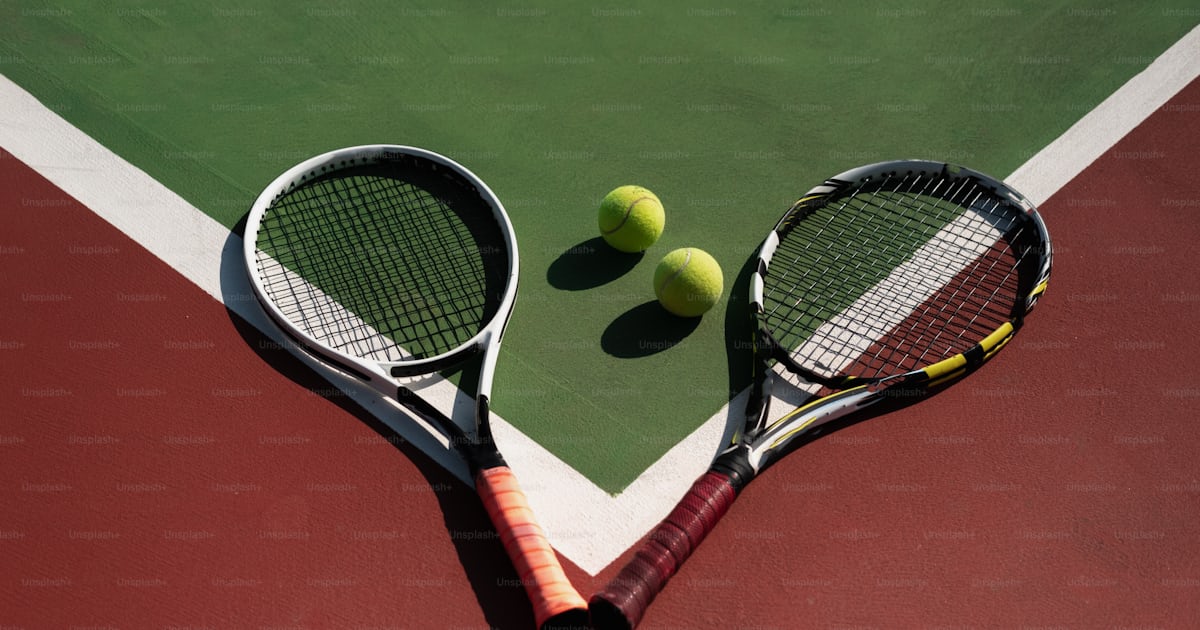 Two tennis rackets and two tennis balls on a tennis court photo ...