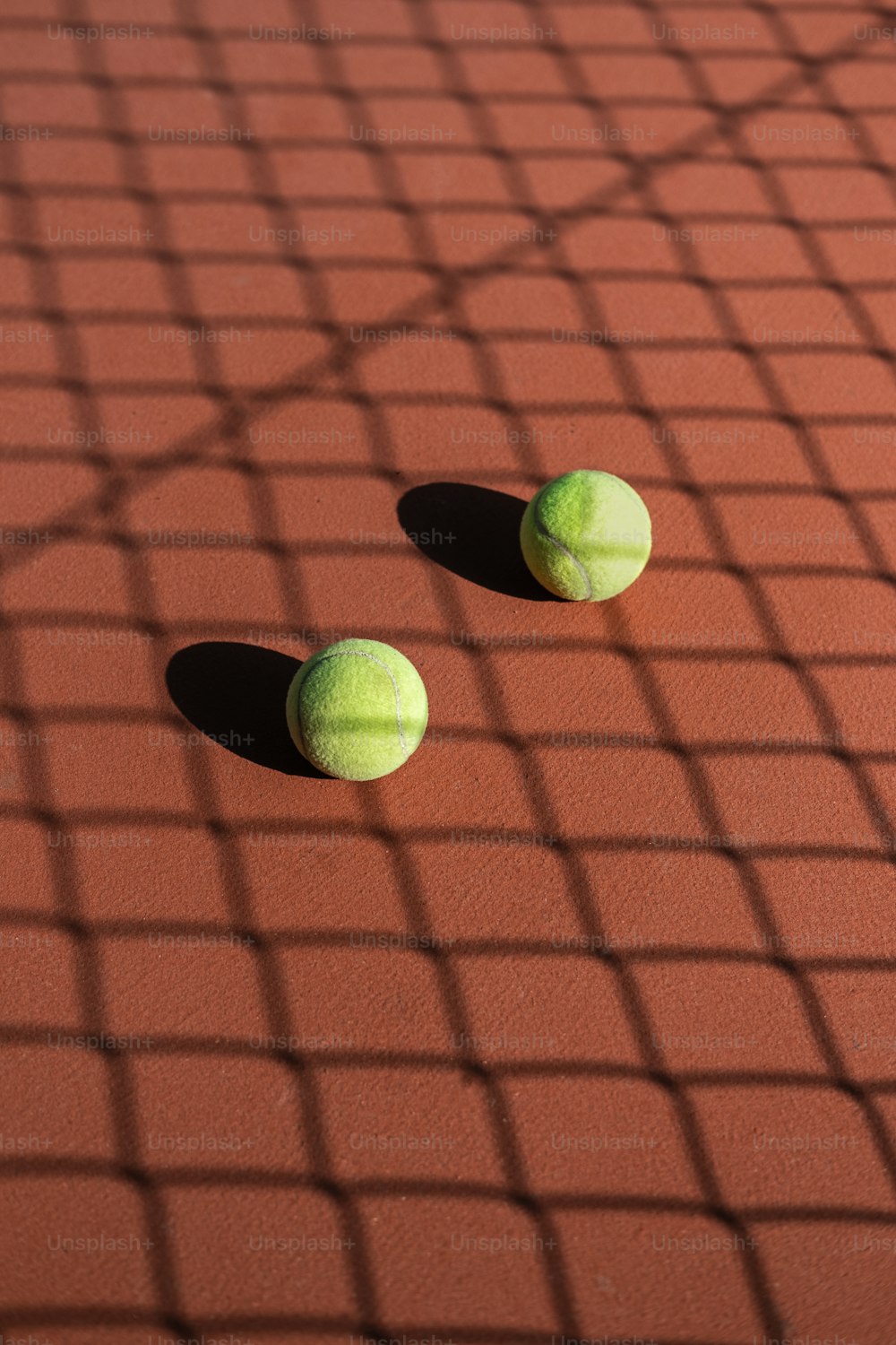 two tennis balls sitting on a tennis court