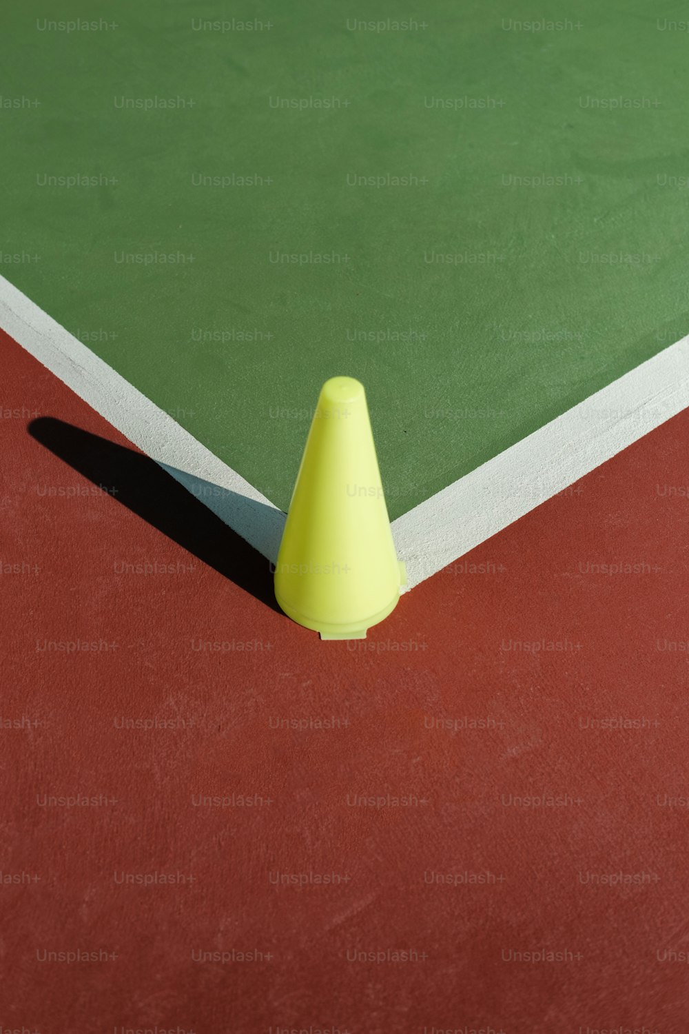 un cono giallo seduto sulla cima di un campo da tennis