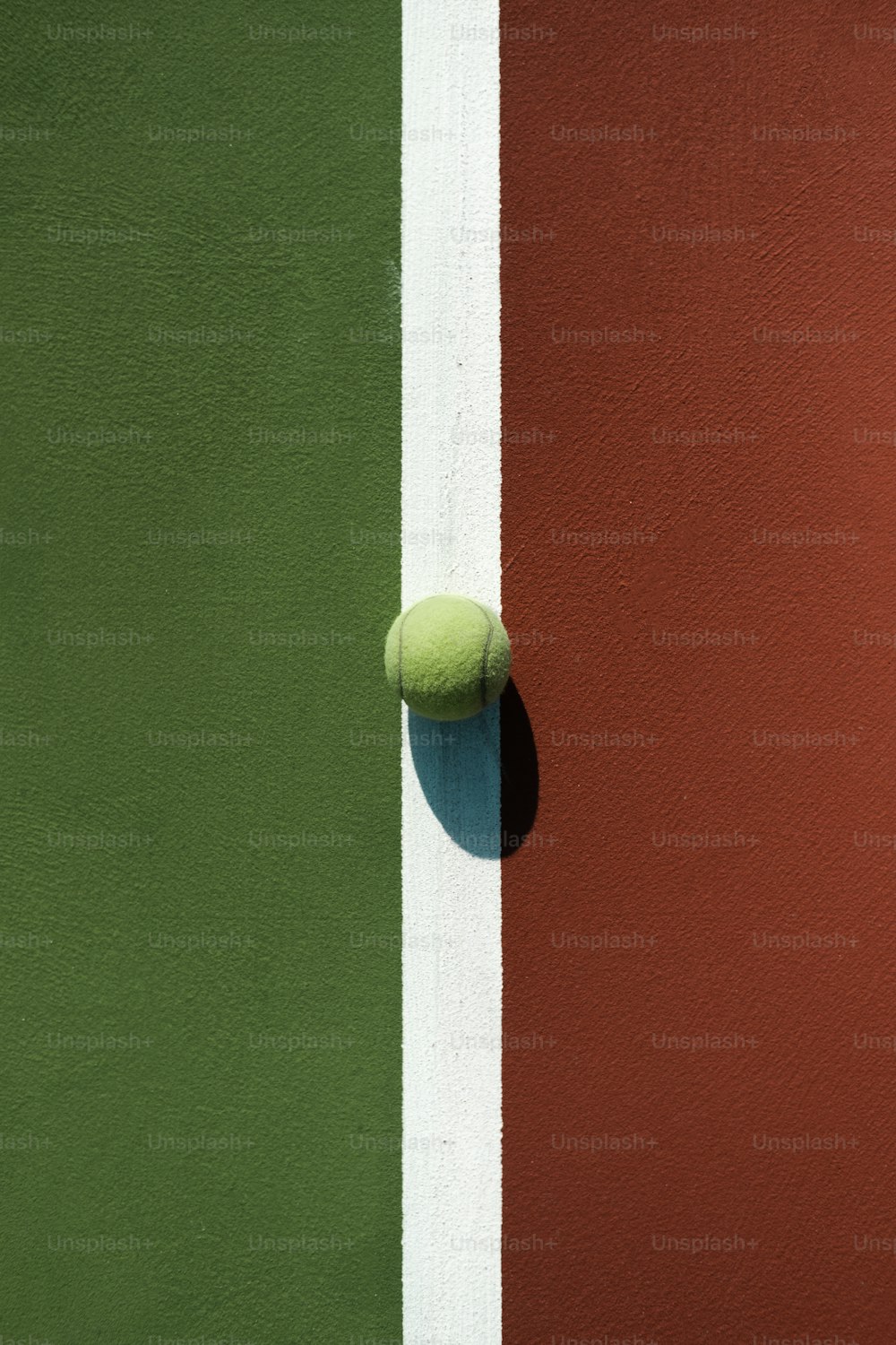 Una pelota de tenis sentada al costado de una cancha de tenis
