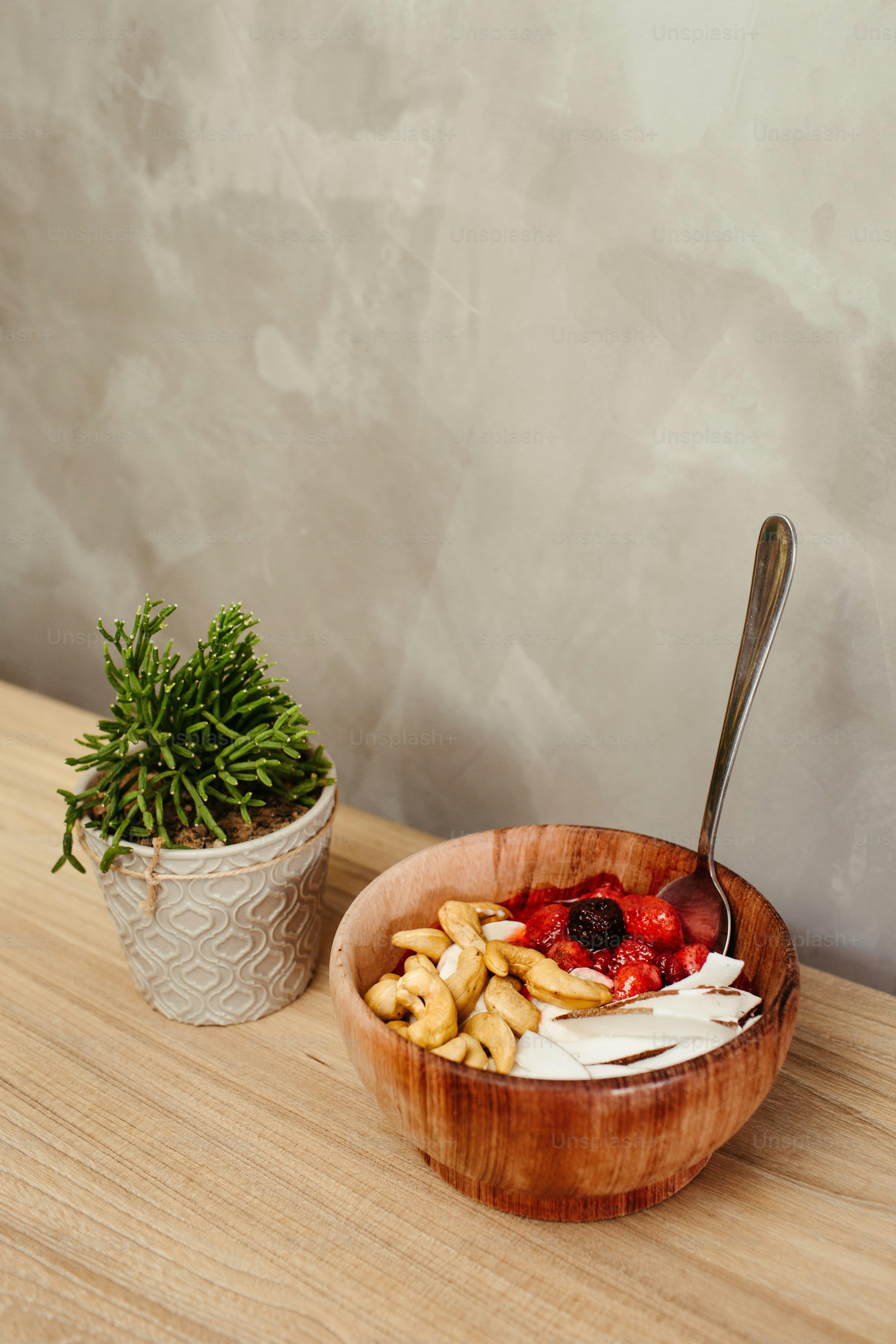a bowl of food with a spoon next to a potted plant