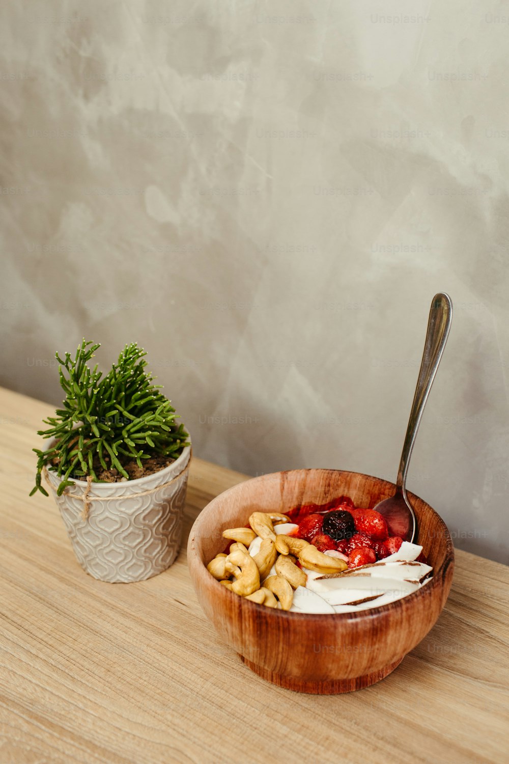 a bowl of food with a spoon next to a potted plant