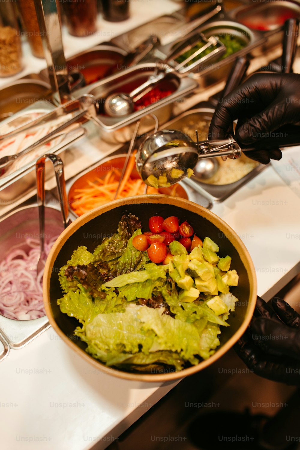 a person in black gloves is serving a salad