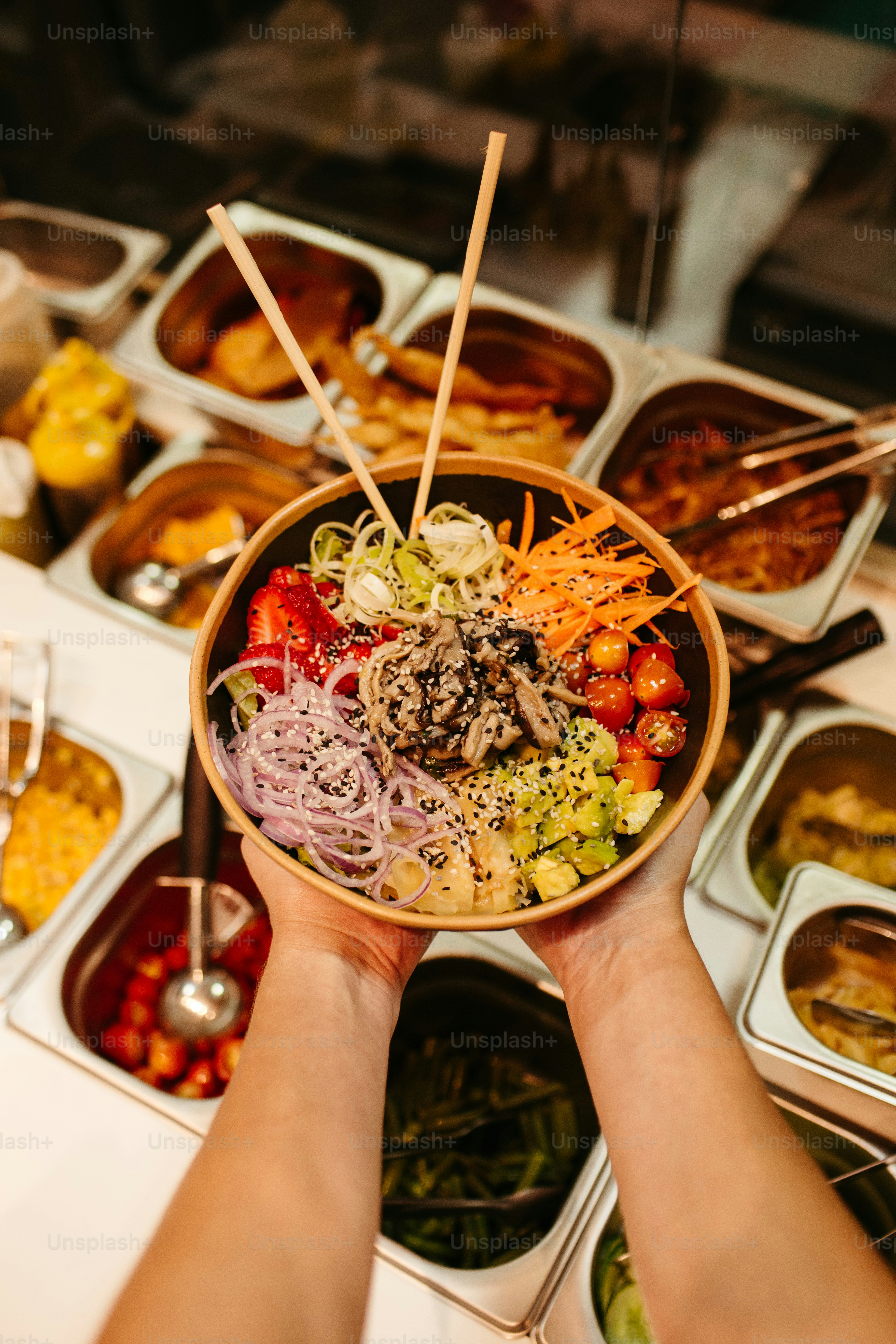 a person holding a bowl of food with chopsticks