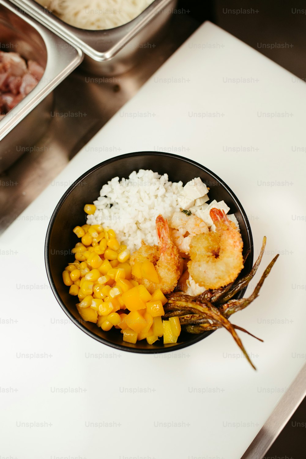 a bowl of shrimp, rice, and corn on a table
