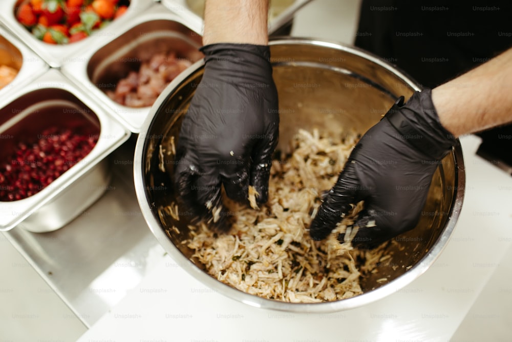 a person in black gloves is mixing food in a bowl