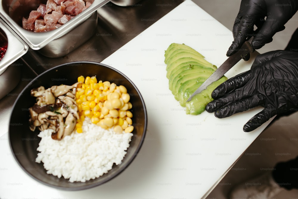 eine Person in schwarzen Handschuhen, die Essen auf einem Schneidebrett zerschneidet