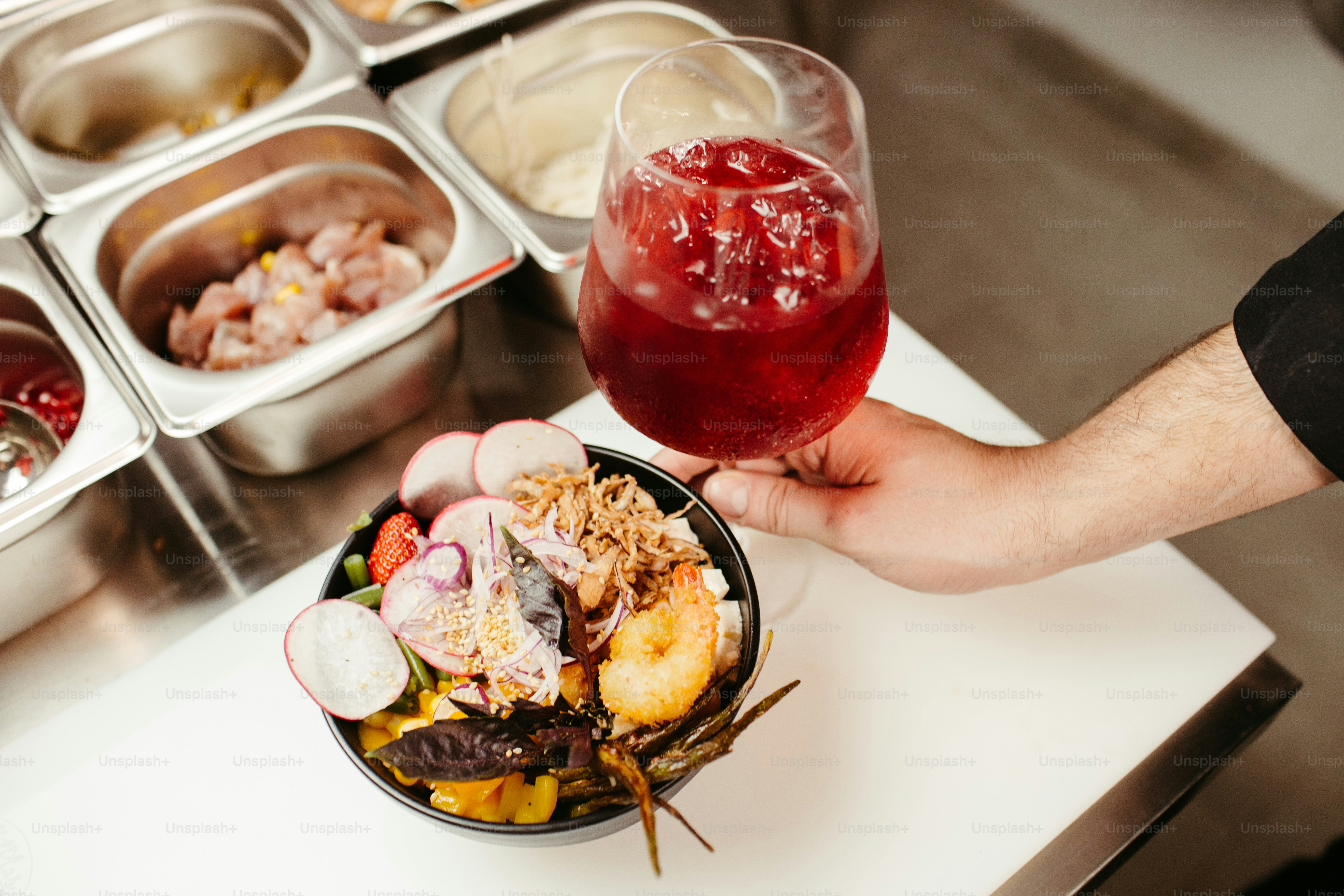 a person holding a wine glass over a bowl of food