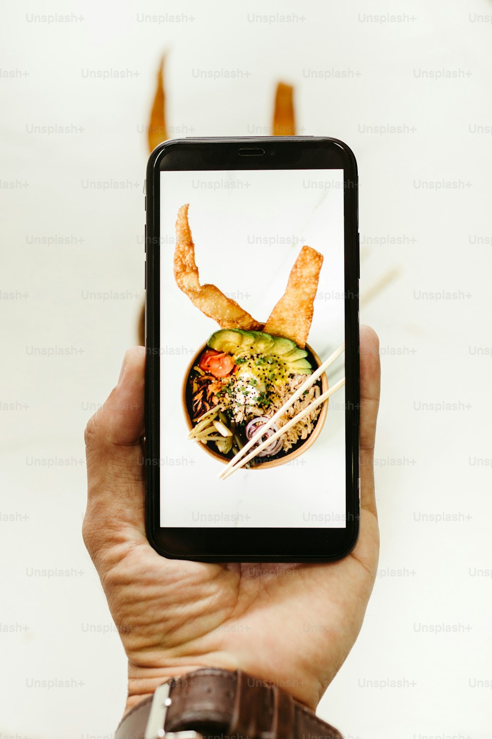 eine Person, die ein Smartphone mit einem Bild einer Schüssel mit Essen in der Hand hält