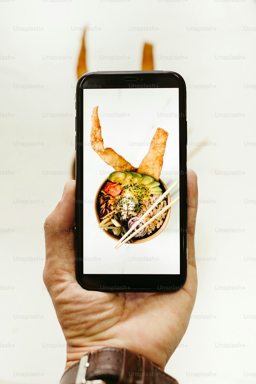 a person holding a smart phone with a picture of a bowl of food on it