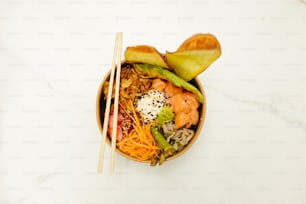 a bowl of food with chopsticks on a table