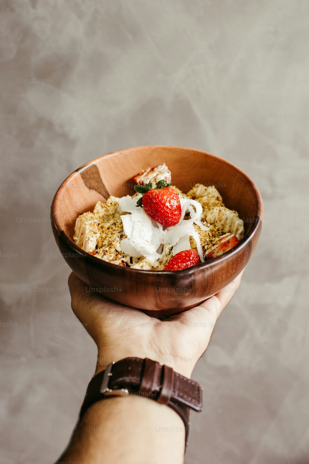 a person holding a bowl of cereal with strawberries