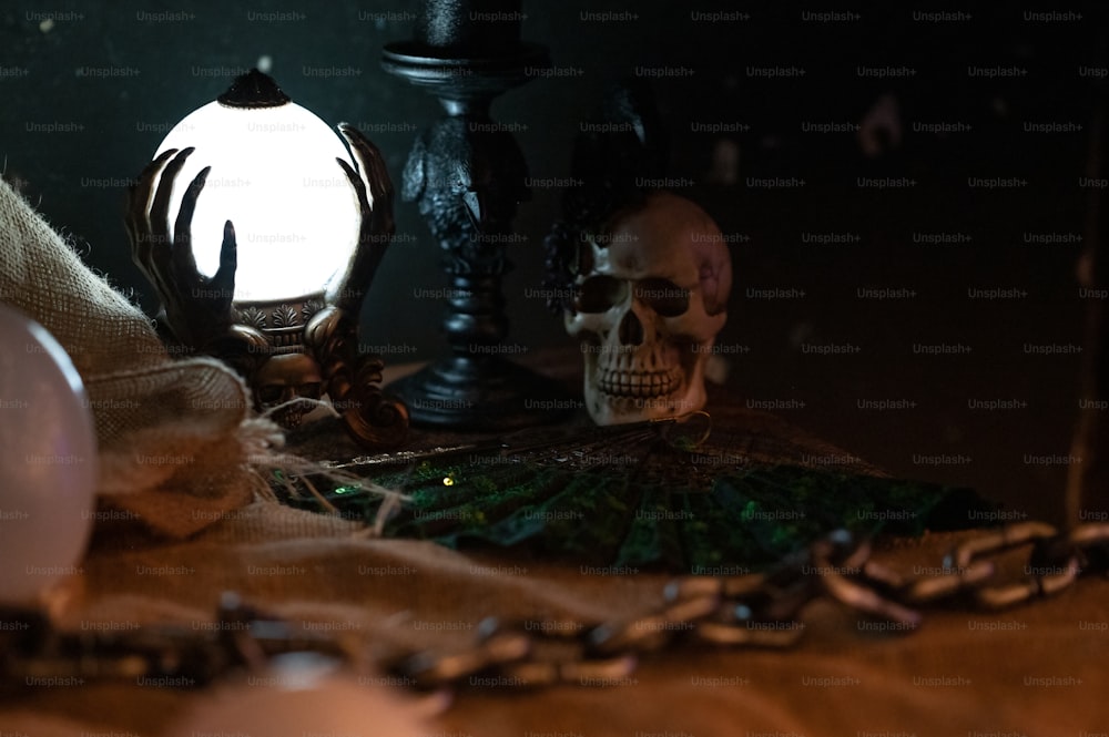 um crânio sentado em cima de uma mesa ao lado de uma luz