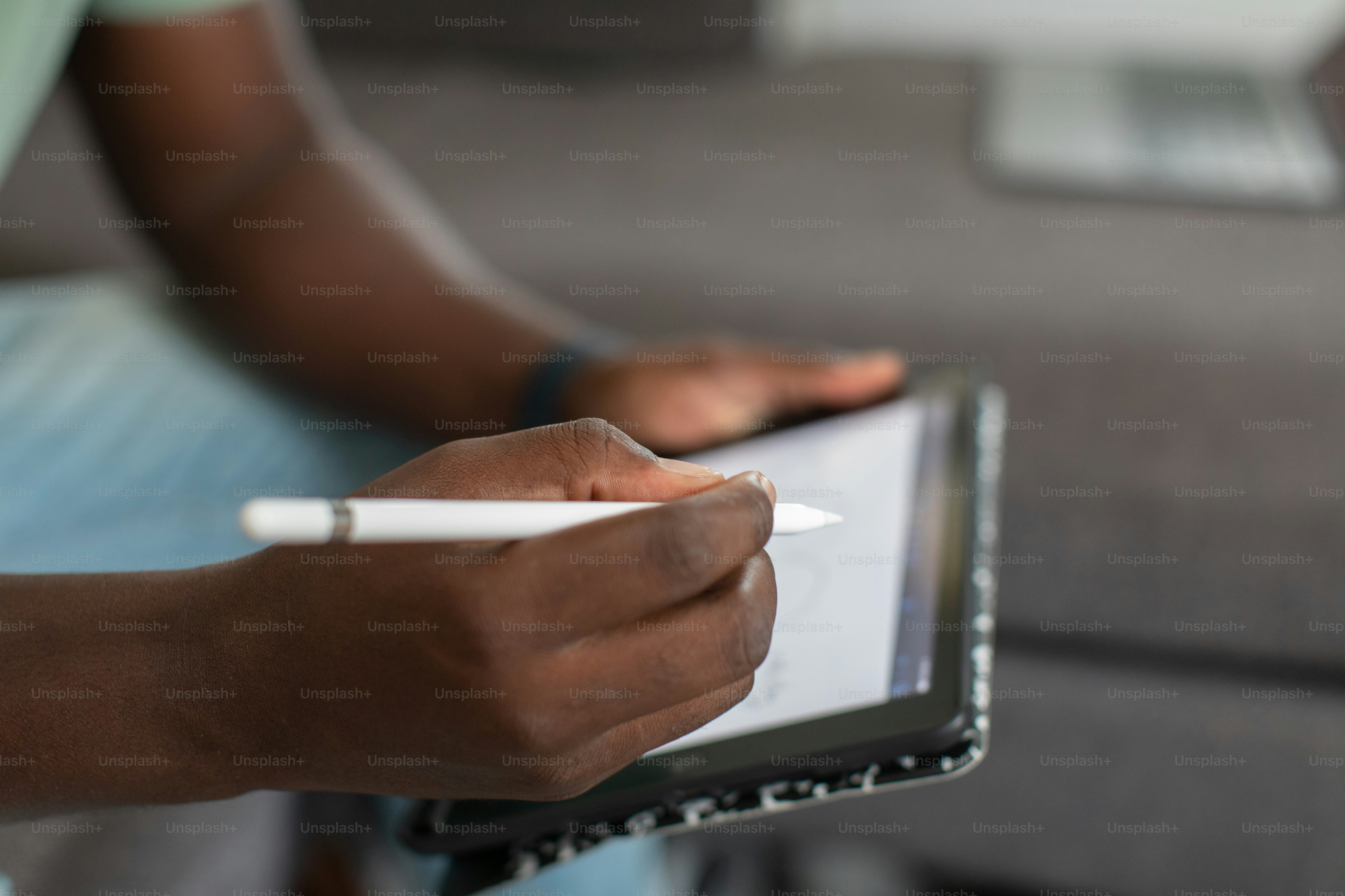 eine Person, die auf einer Couch sitzt und ein Tablet in der Hand hält