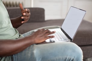 Un hombre sentado en un sofá usando una computadora portátil