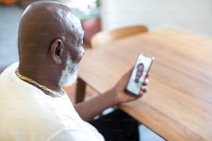 Un uomo seduto a un tavolo con in mano un telefono cellulare