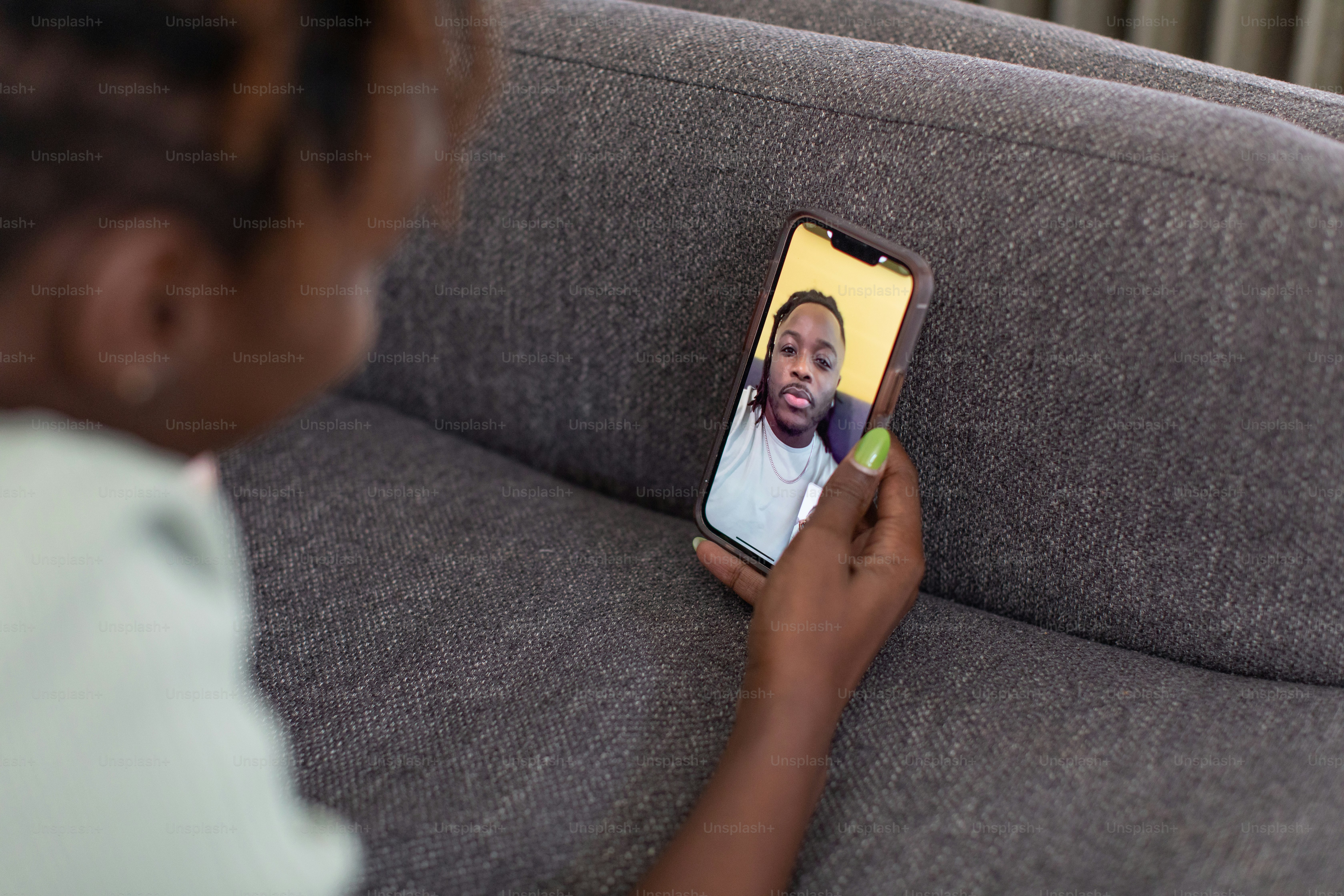 a woman sitting on a couch looking at a cell phone