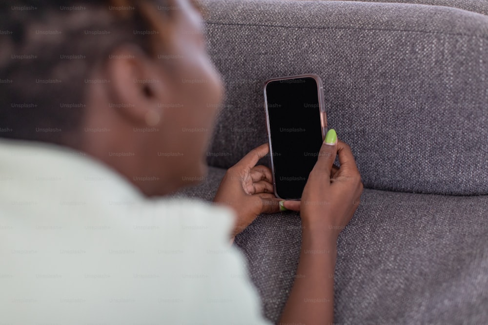 Una mujer sentada en un sofá usando un teléfono celular