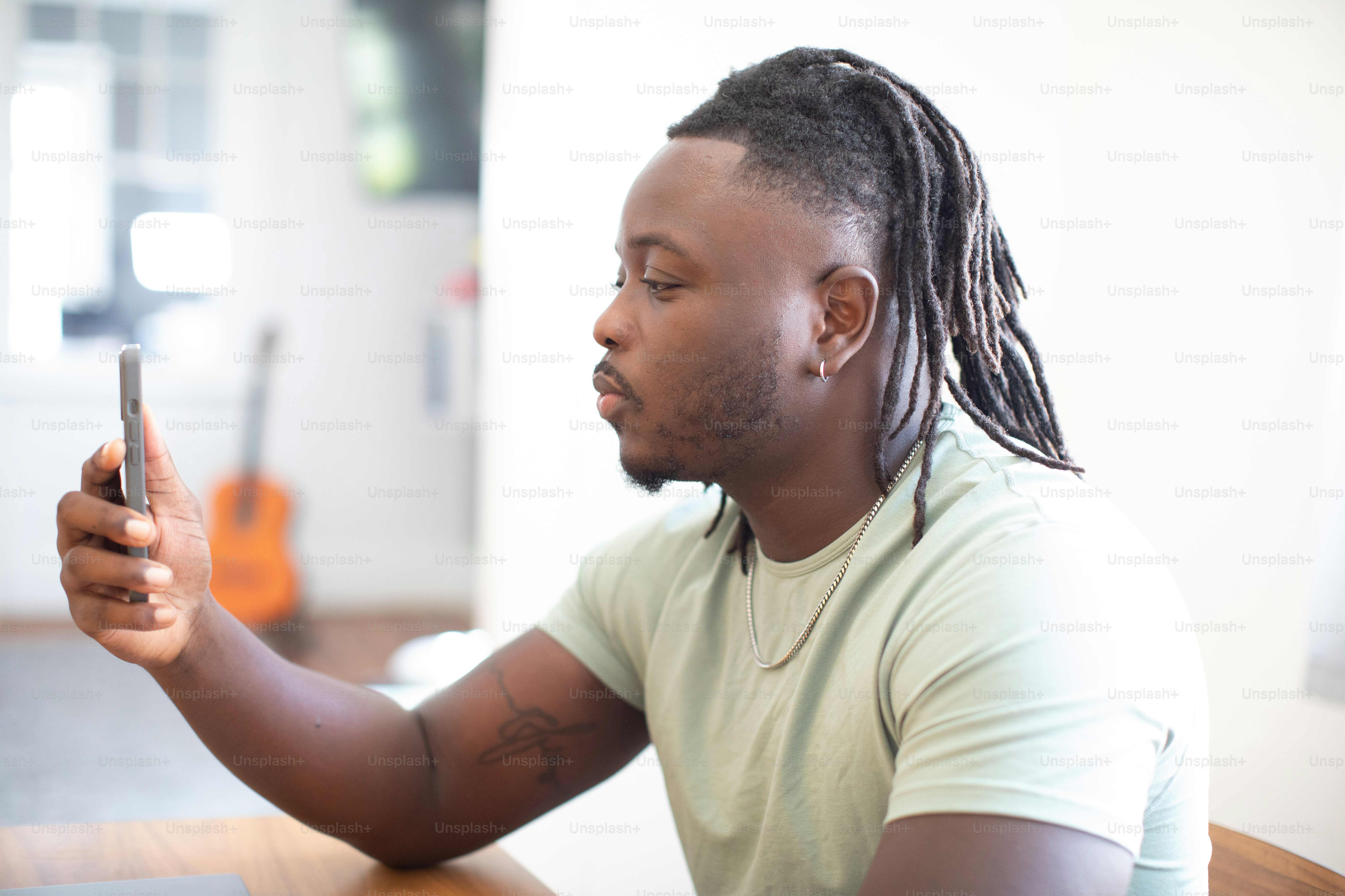 Un uomo seduto a un tavolo che guarda il suo cellulare