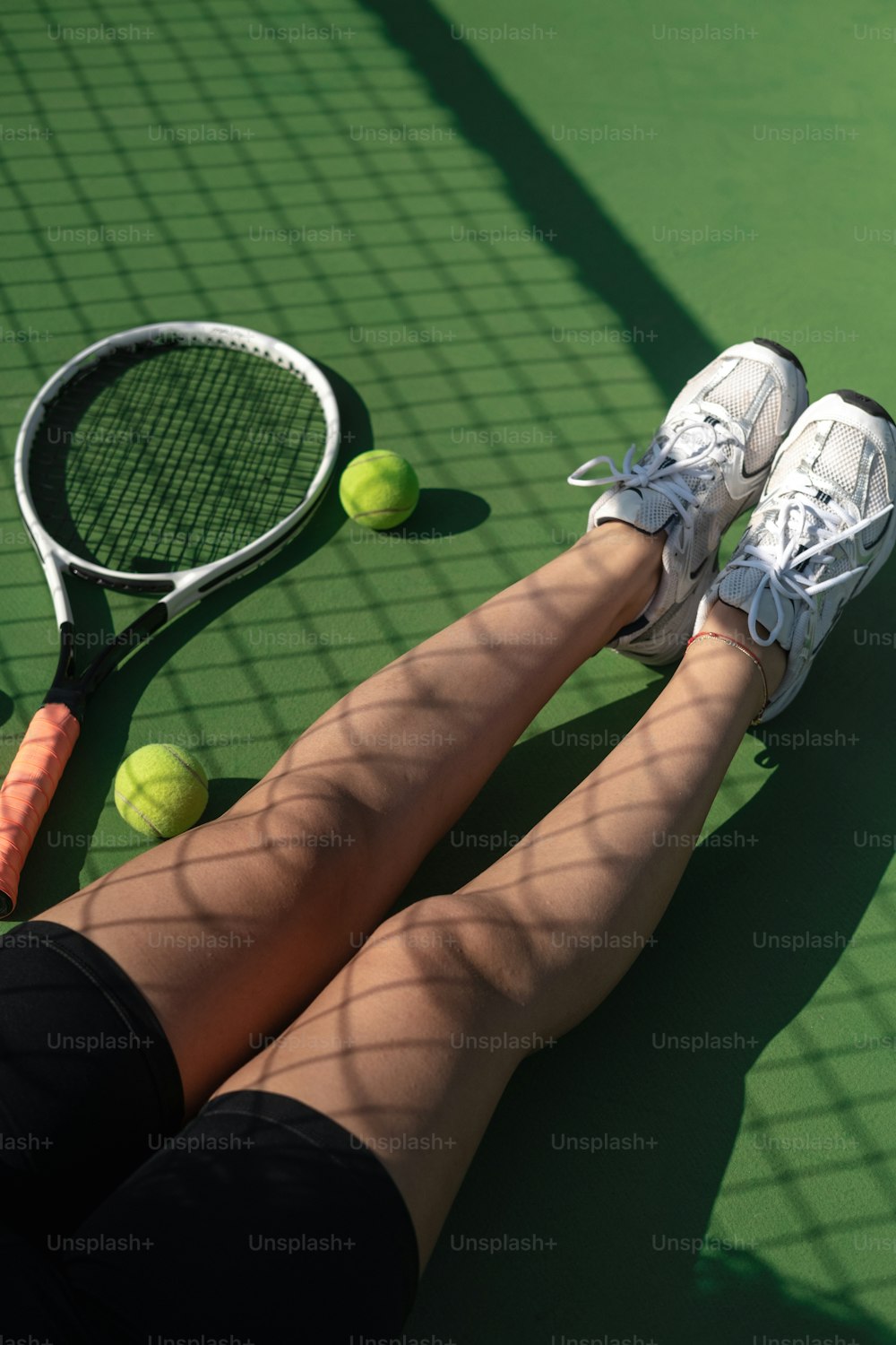 uma pessoa deitada em uma quadra de tênis com uma raquete