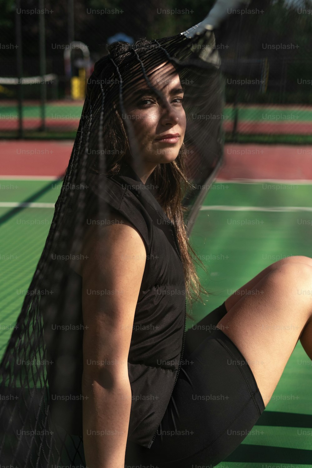 a woman sitting on a tennis court holding a racket