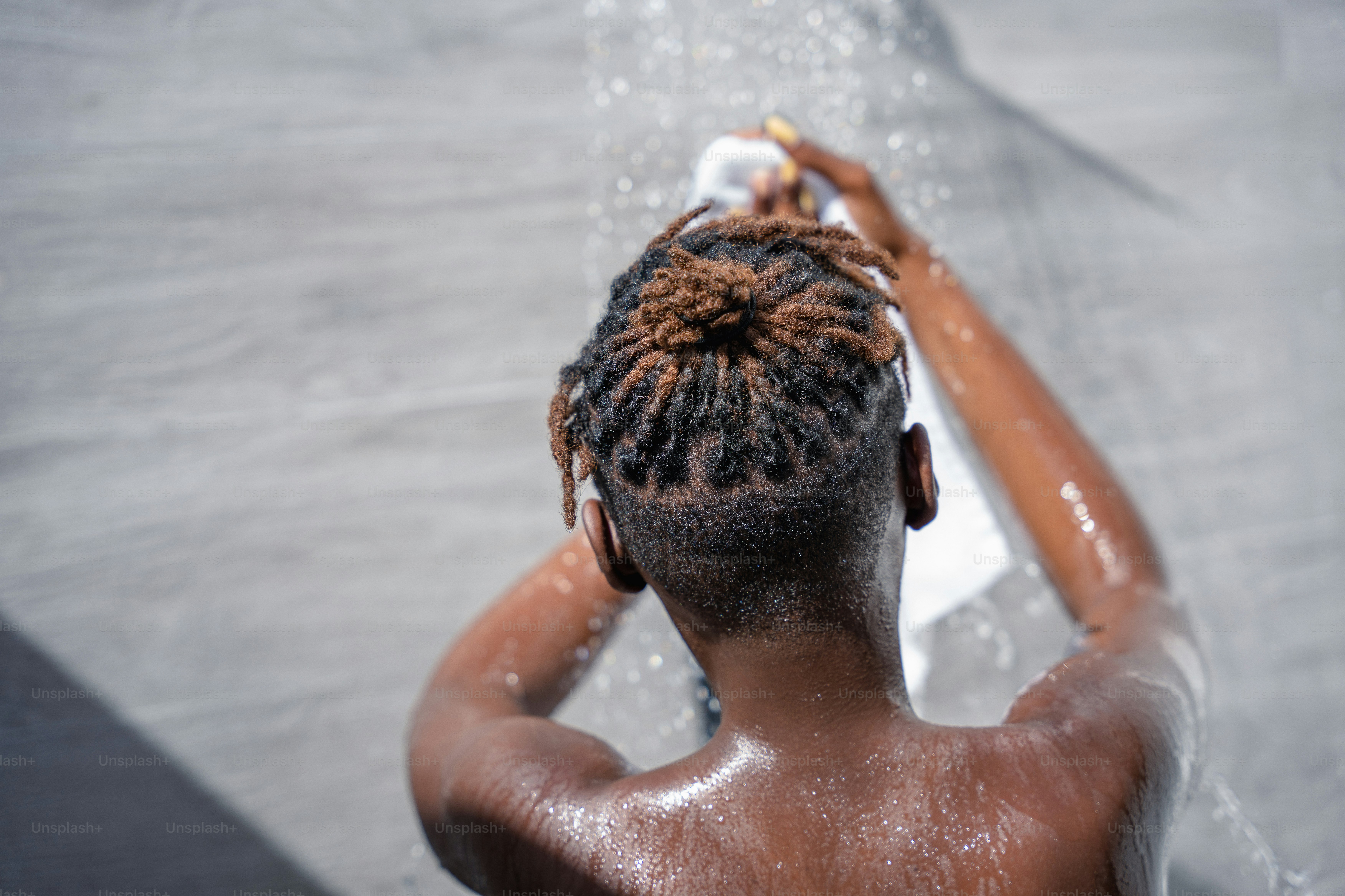 A person with dreadlocks standing under a shower head photo Shower