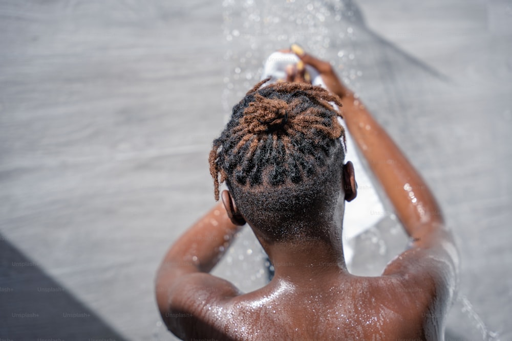 a person with dreadlocks standing under a shower head