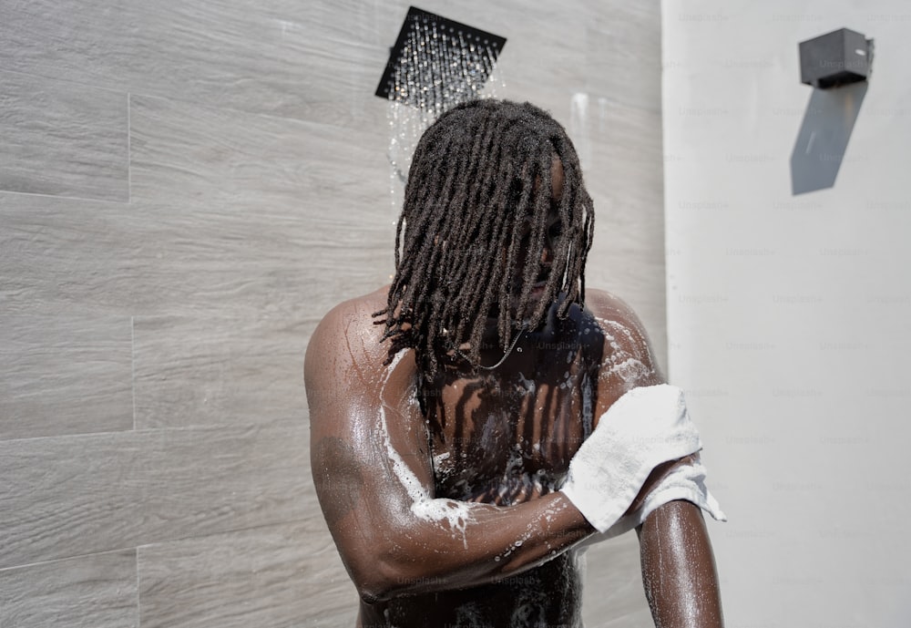 Un uomo con i dreadlocks in piedi in una doccia
