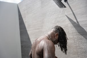 a man with dreadlocks standing under a shower head