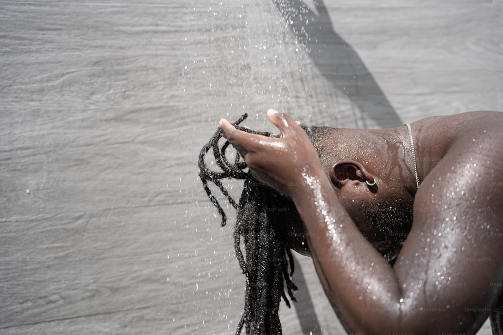 a man with dreadlocks standing under a shower head