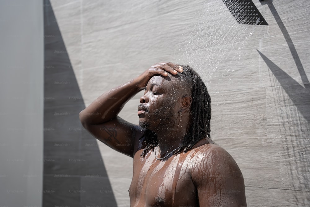 a man with dreadlocks standing under a shower head