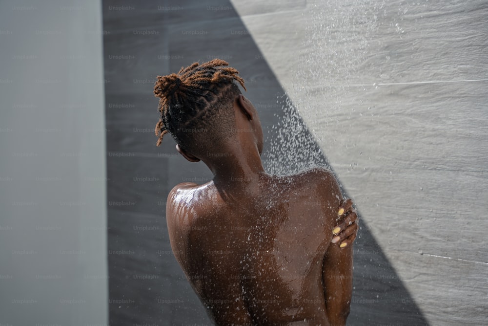 a woman with dreadlocks standing in a shower
