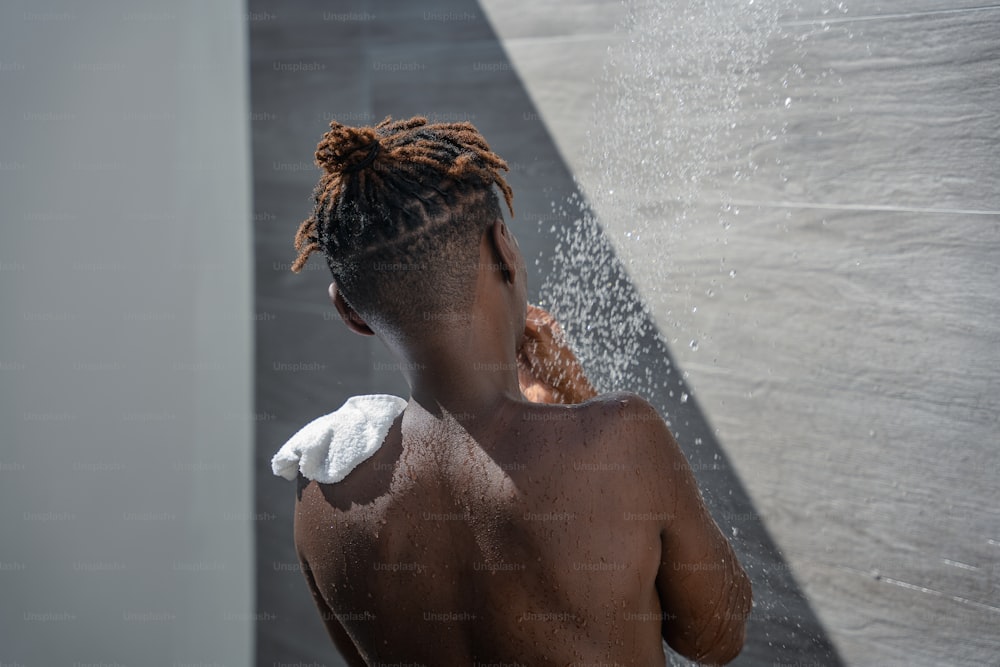 Una donna con i dreadlocks in piedi in una doccia