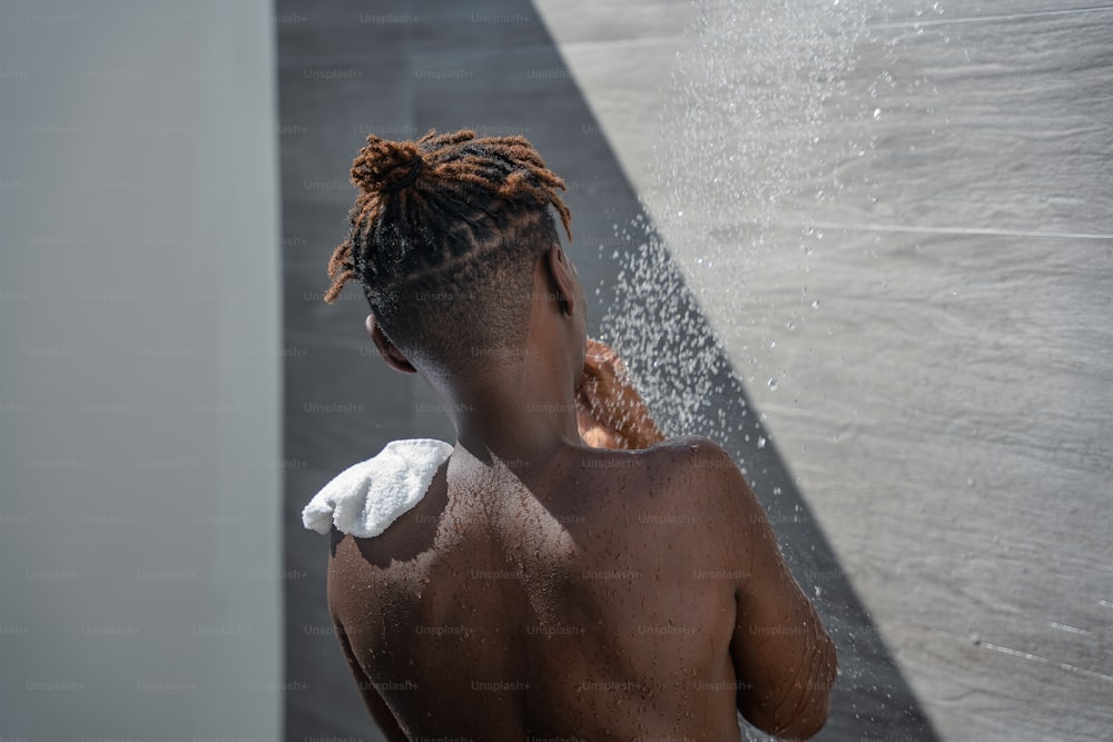 a woman with dreadlocks standing in a shower