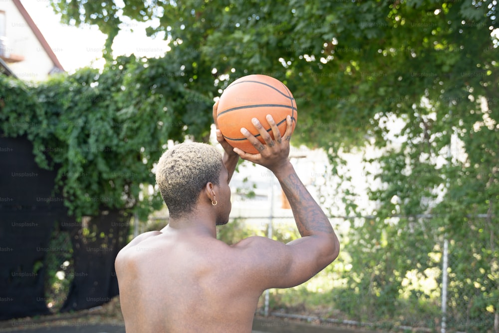 Un uomo che tiene un pallone da basket fino al viso