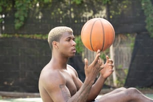 Un hombre sin camisa sosteniendo una pelota de baloncesto en la mano