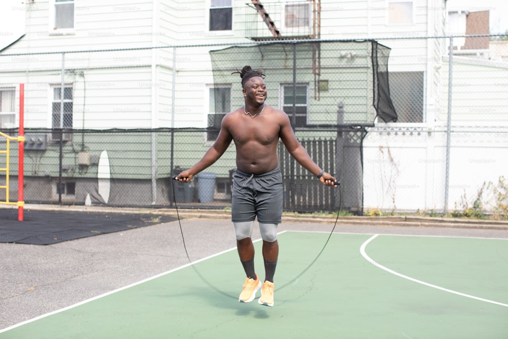 a shirtless man on a basketball court holding a rope