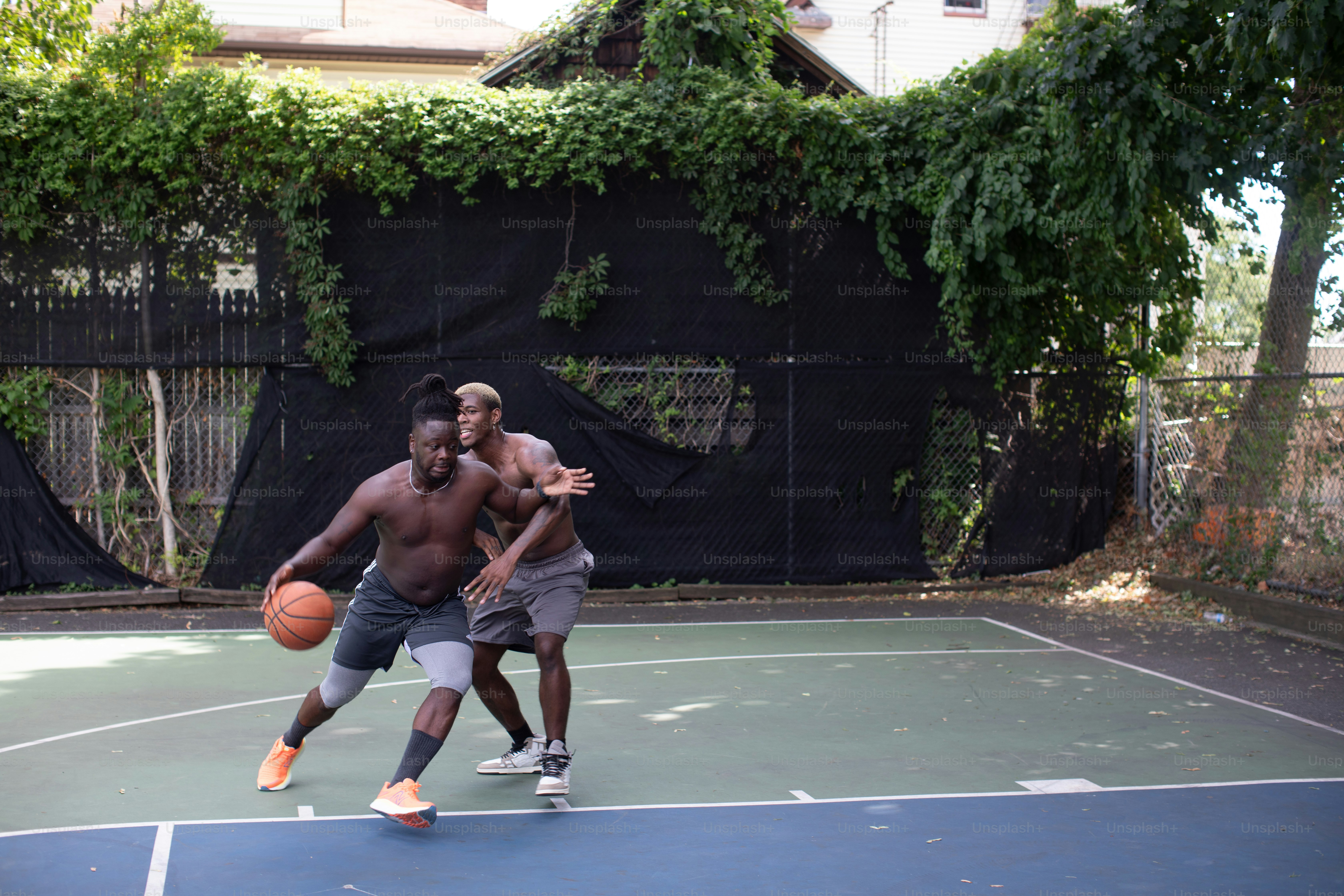 two young men playing a game of basketball on a court