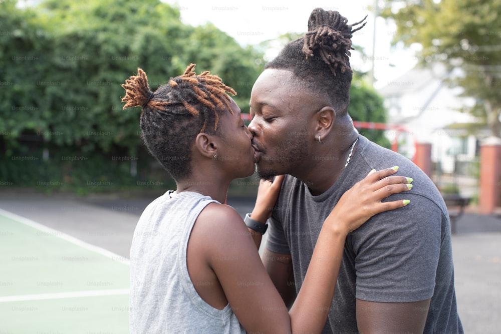 um homem e uma mulher se beijando em uma quadra de tênis