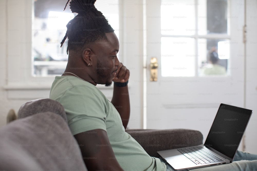 a man sitting on a couch using a laptop computer