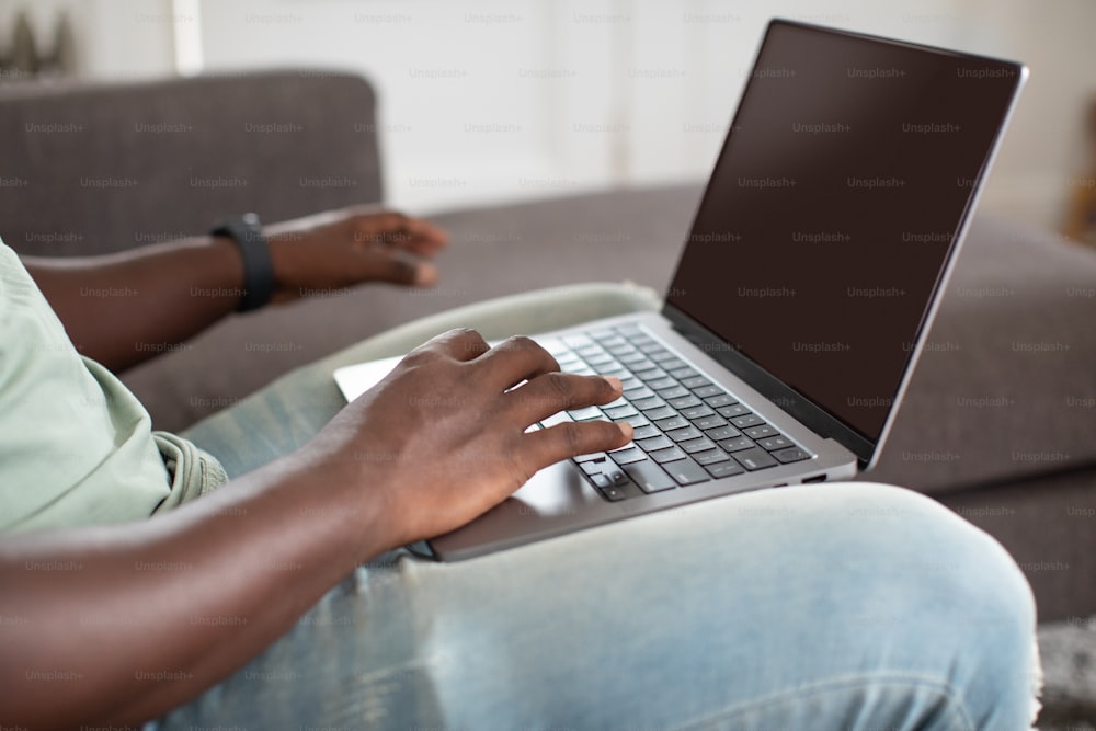 um homem sentado em um sofá usando um computador portátil