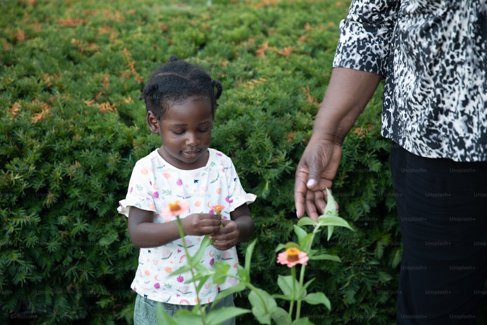 a little girl standing next to a woman in a field