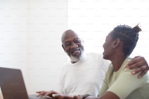 a man and a woman sitting in front of a laptop computer