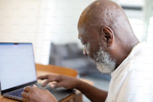 um homem sentado em uma mesa usando um computador portátil
