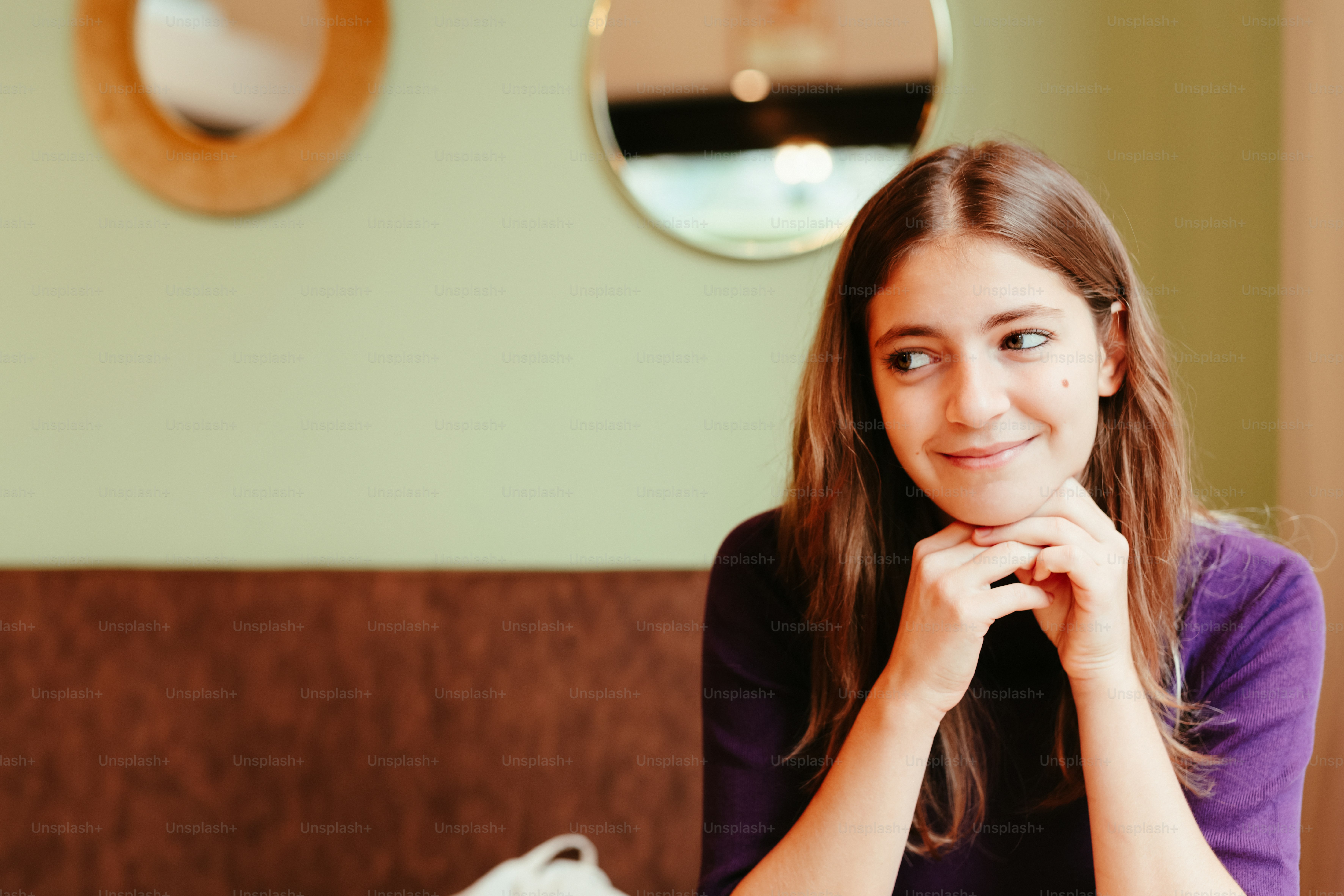A woman sitting at a table with her hand on her chin photo – Head on ...