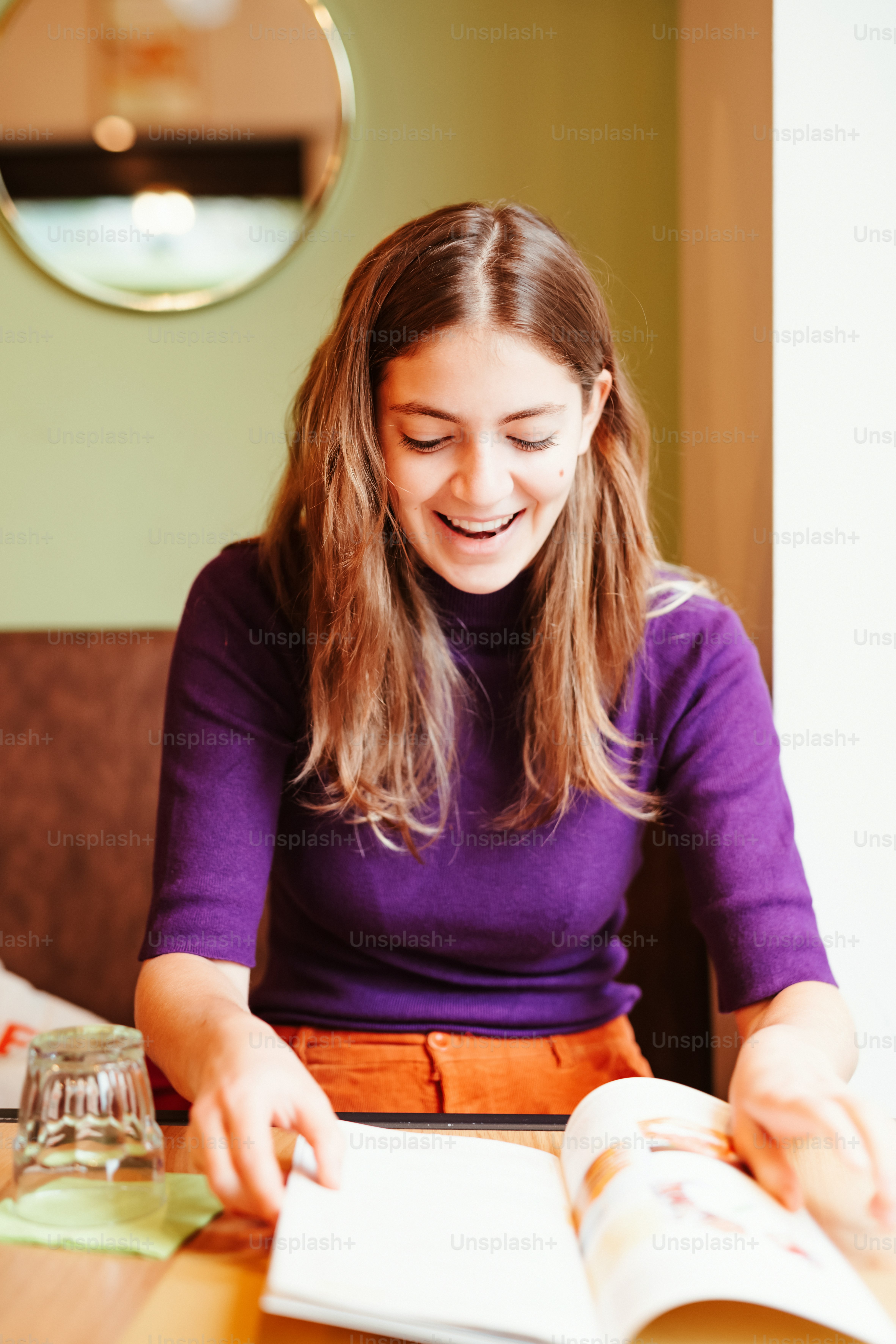 a woman sitting at a table reading a book
