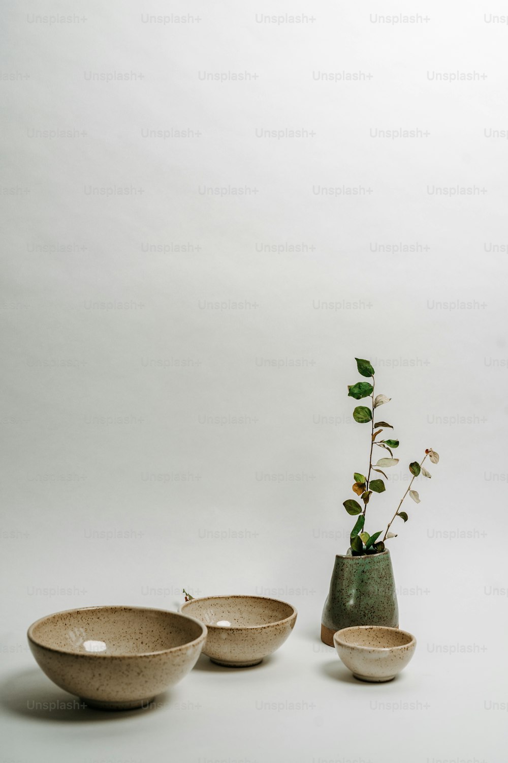 a couple of bowls sitting next to a vase with a plant in it