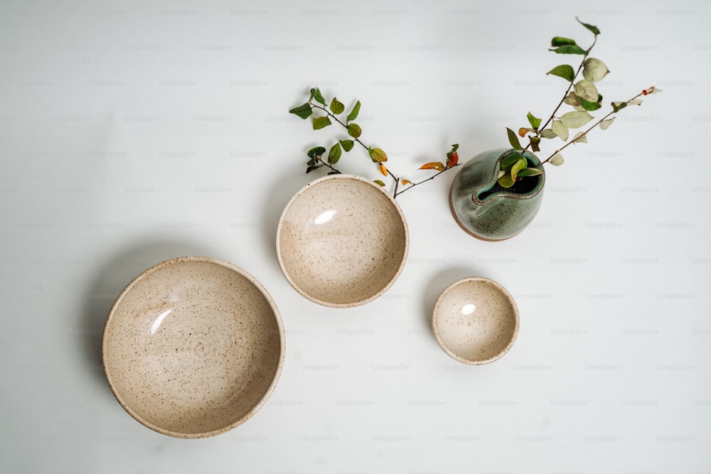 three bowls and a vase on a white surface