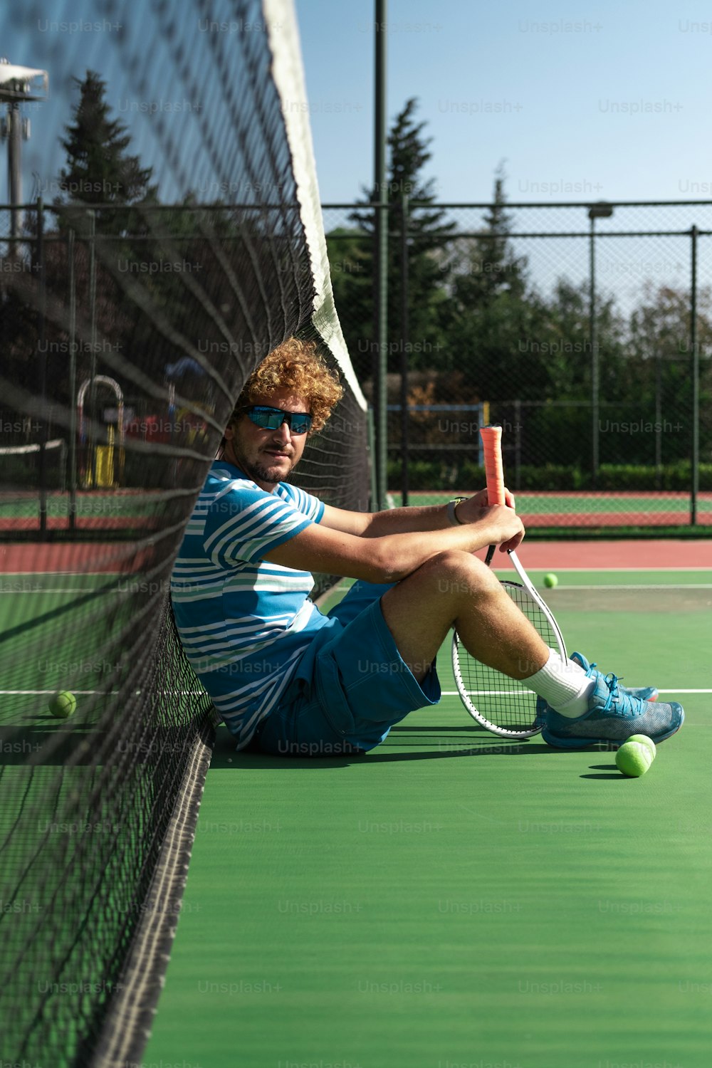 um homem sentado em uma quadra de tênis segurando uma raquete
