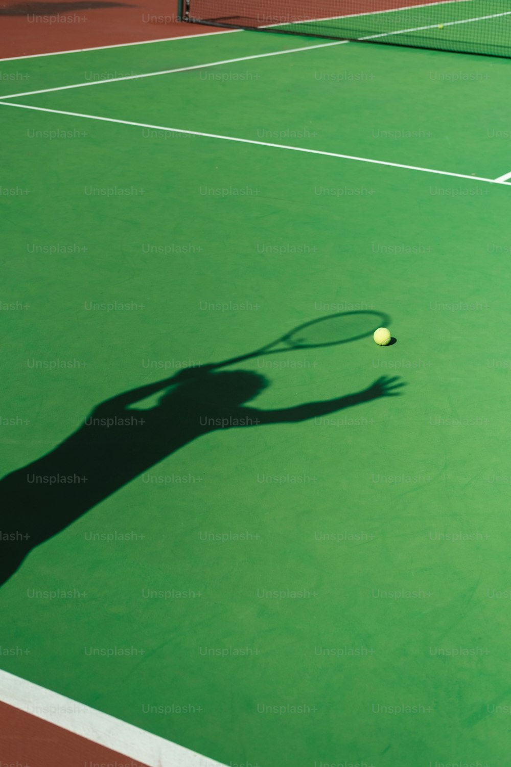 Ein Schatten einer Person, die auf einem Tennisplatz Tennis spielt